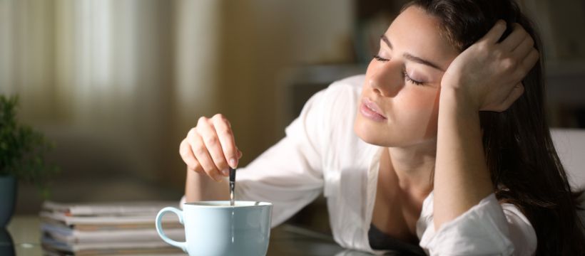Sleepy looking woman slumped on a desk for seasonal. affective. disorder article.